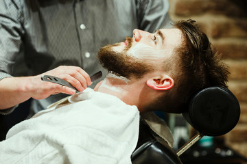 Barber shaving a bearded man