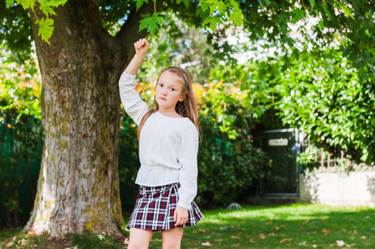 Outdoor portrait of a cute little girl dressed in schoolwear