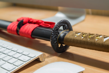 Japanese katana sword on a computer table in office room
