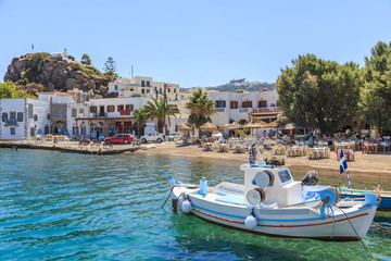Greek island of Patmos belongs to the Dodecanese. Fragment of the fishing port and beach in the town of Skala. On the hill visible town Chora and Monastery of St. John's - 91333907
