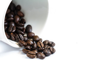Coffee beans spilled from the coffee cup in the white background
