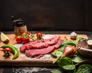 ingredients for cooking turkey steak on a wooden cutting board on a dark wooden background close up