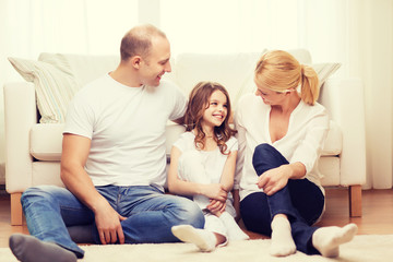 parents and little girl sitting on floor at home