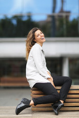 Happy woman sitting on a bench smiling