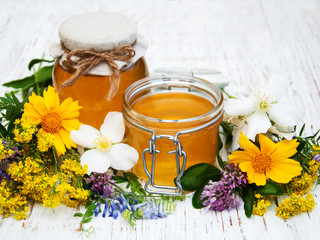 Honey and wild flowers on a wooden background