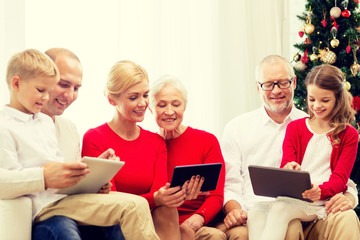 smiling family with tablet pc computers at home