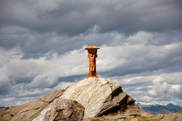 A wooden sculpture placed in the high mountains with black clouds