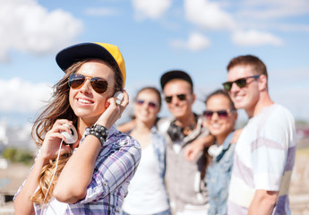 teenage girl with headphones and friends outside