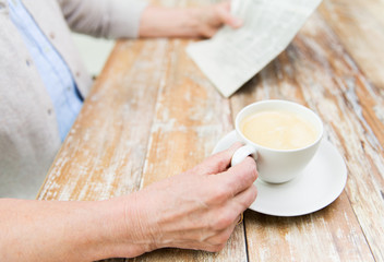senior woman with coffee reading newspaper at home