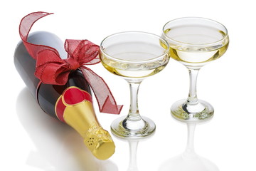 Festive champagne bottle with red bow knot and two glasses over white background.