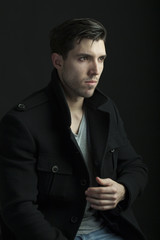 young attractive man in a coat  on black background