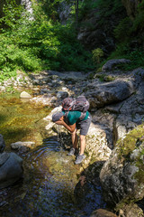 Naklejka na ściany i meble Hiker washing in a mountain river