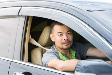 Asian man driving his car and looking out of the window's car process in warm tone