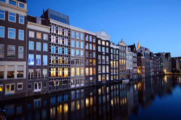 Fototapeta premium Typische Häuserfront vor Gracht in Amsterdam bei Nacht
