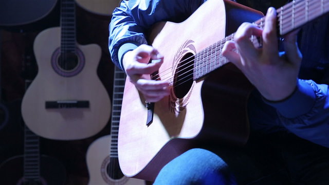 Musician playing on acoustic guitar.