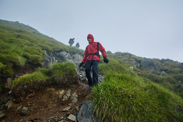Fototapeta na wymiar Hikers in raincoats on mountain