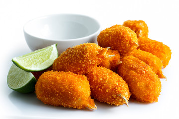 Pile of fried breaded surimi crab claws with empty dip bowl and