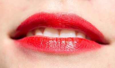 Close-up shot of woman lips with glossy red lipstick