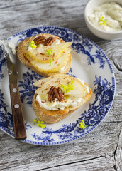bruschetta with cheese, pear, honey and nuts on the oval plate on a light wooden surface
