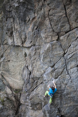Young woman with rope climbs on the rock.