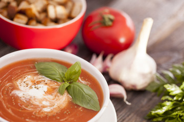 Delicious tomato soup with aromatic spices on a wooden table.