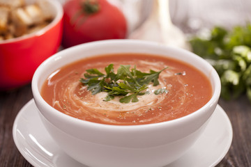 Delicious tomato soup with aromatic spices on a wooden table.