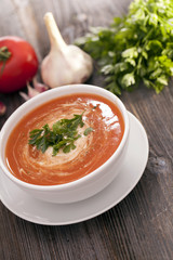 Delicious tomato soup with aromatic spices on a wooden table.