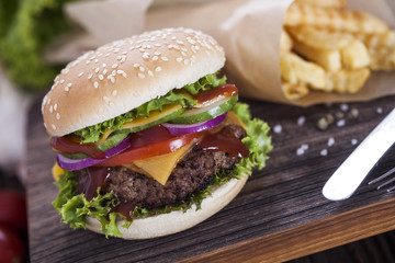 Beef burgers on a wooden board with chips and aromatic spices.