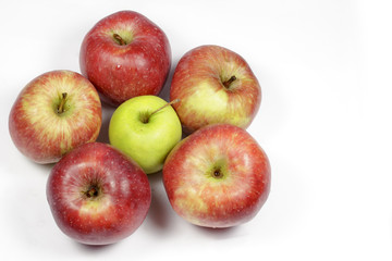 Green apple surrounded by red apples with blank space at right