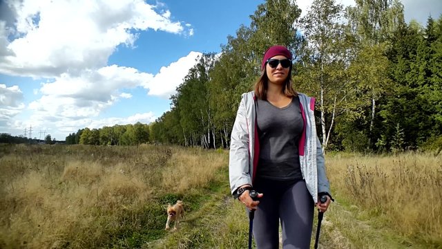 Young woman goes Nordic walking outdoors with small dog Griffon Bruxellois breed