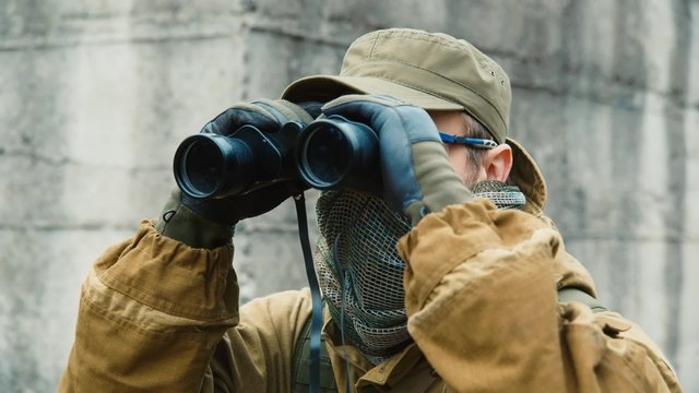 Man in camouflage looking through binoculars