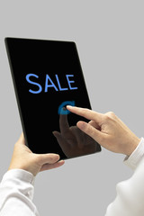 Sale message on digital tablet computer display. Woman hands wit