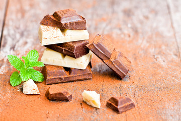 Pile of chocolate slices with mint on an old wooden table.