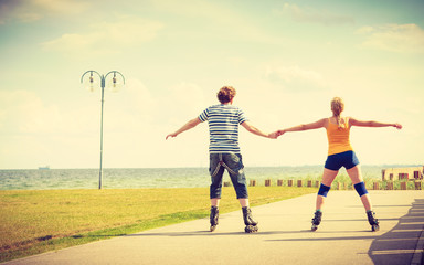 Obraz premium Young couple on roller skates riding outdoors