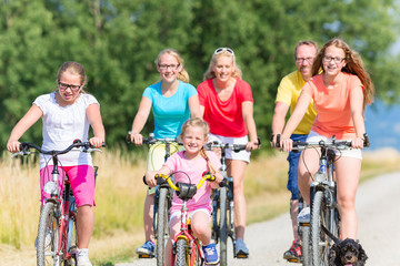 Familie fährt Fahrrad auf Feldweg, Mutter, Vater und Kinder gemeinsam