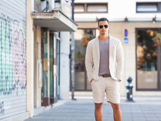 Portrait of handsome young man standing on the street with his hands in pockets