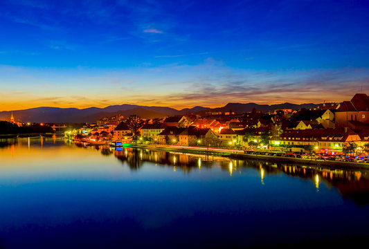 Beautiful view of Maribor city by river Drava at night after sunset with twilight blue sky and city lights, Slovenia.