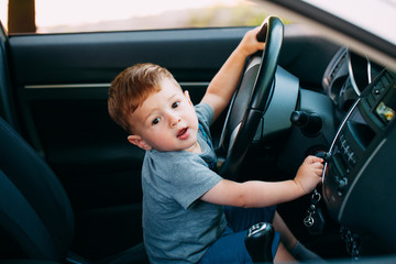 Cute little boy driving fathers car
