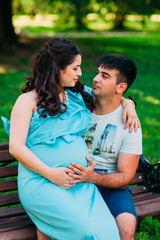 Beautiful pregnant couple relaxing outside in the park.