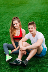 Young athletic couple sitting on the grass