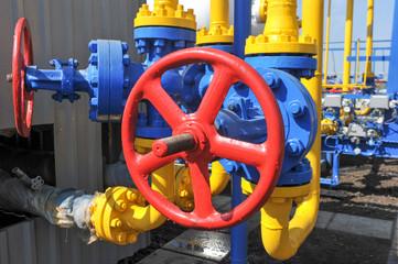 Red faucet with steel pipe in natural gas treatment plant in bright sunny summer day