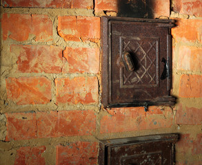 Rusty closed metal door in red brick sooty furnace