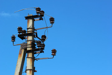 Old rusty electrical pole with insulators and broken wires
