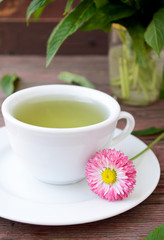 Cup of herbal tea with wild camomiles, mint and flowers