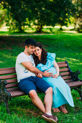 Beautiful pregnant couple relaxing outside in the park.