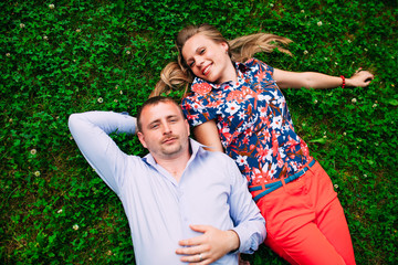 Young couple lying on the grass with a small dog