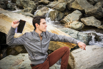 Man on Big Rocks at the River Throwing Something