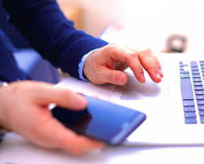 Businessman at a table with a smartphone and a laptop