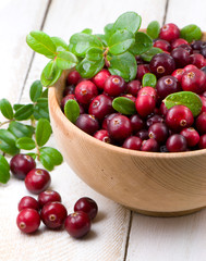 Cowberry with green leaflets in wooden cup