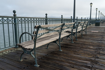 Fototapeta na wymiar Park benches along a wooden pier